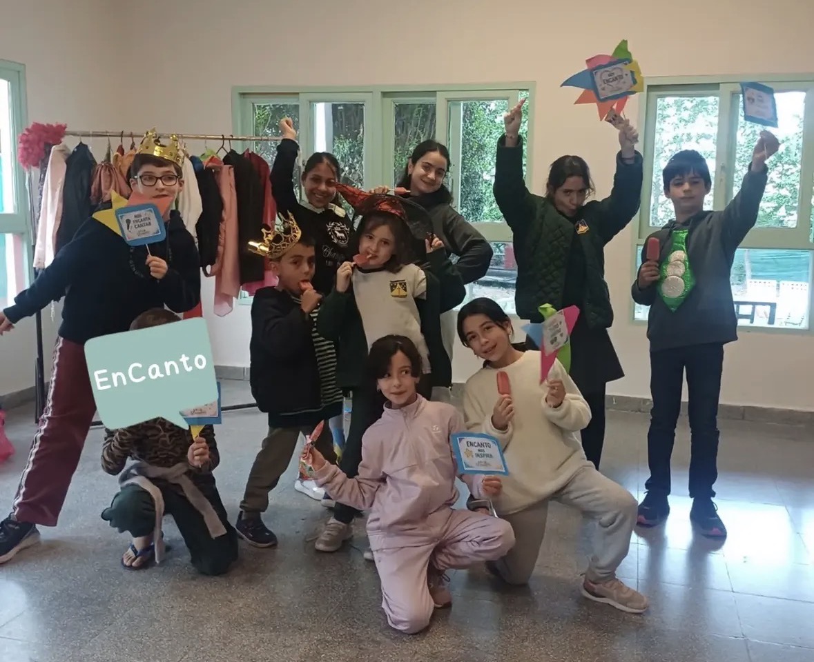 Grupo de chicos de Encanto posando con coronas, sombreros y carteles al final de un taller