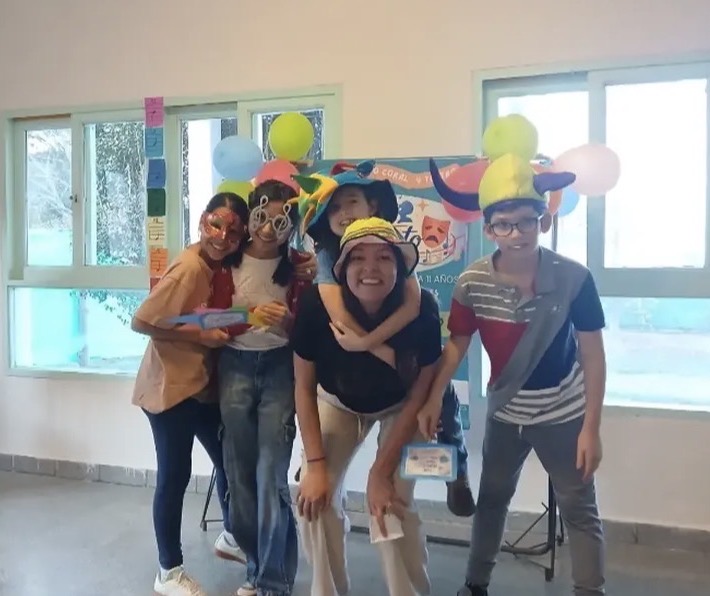 Alumnos y profe de Encanto con sombreros y antifaces de colores